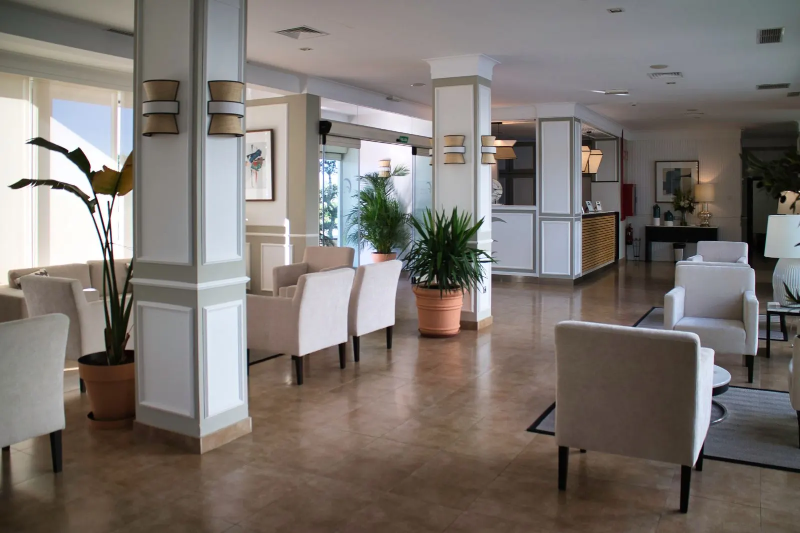 Recepción y zonas comunes del Hotel Las Bóvedas con sillones claros y plantas