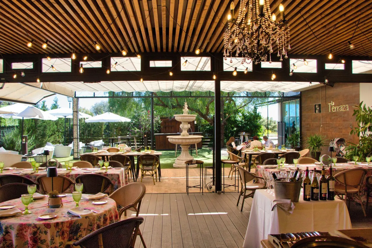 Terraza de Las Bóvedas con fuente, pérgola y mesas con manteles de flores