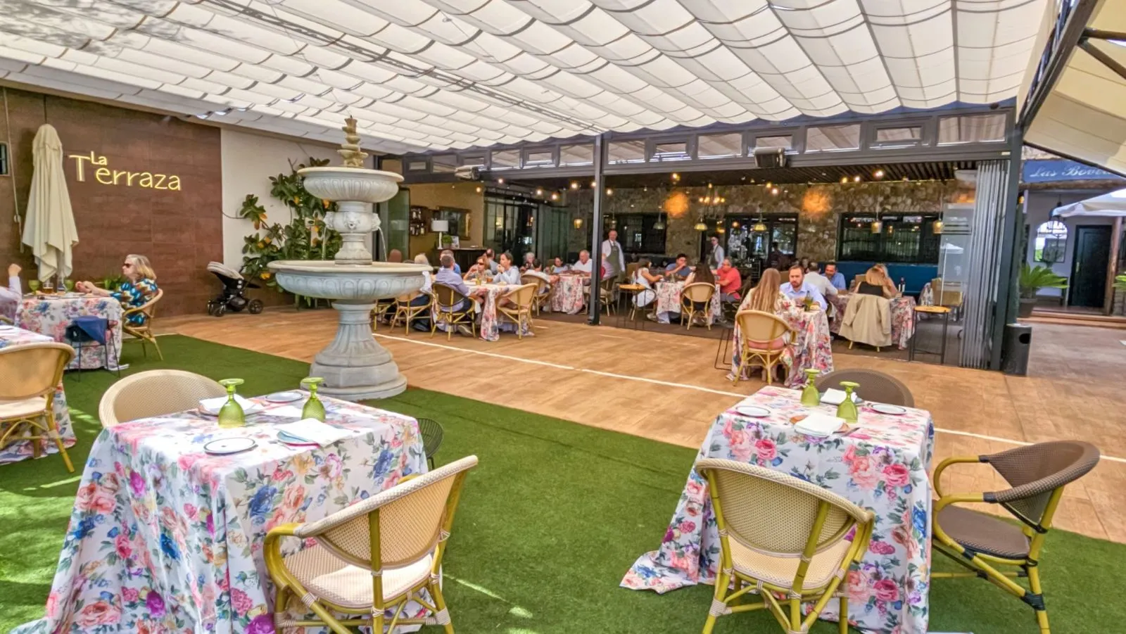 Terraza de Las Bóvedas con fuente, pérgola y mesas con manteles de flores